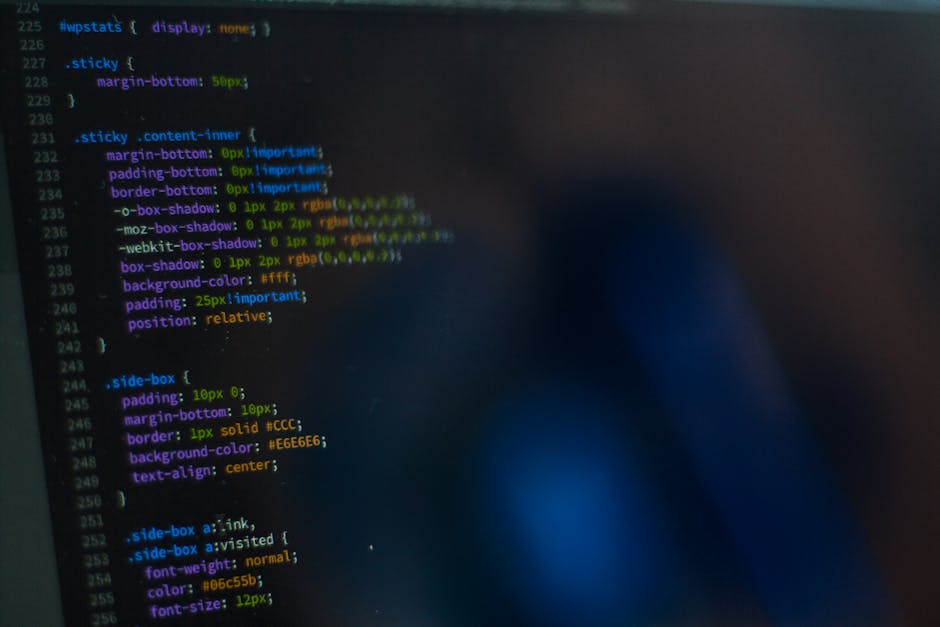 A close-up view of a laptop displaying a software development environment with code in XML or HTML on the left side of the screen and a large, orange calculator interface on the right. The code includ